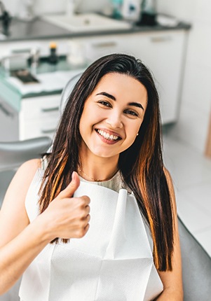 Woman smiling giving thumbs up in dental chair