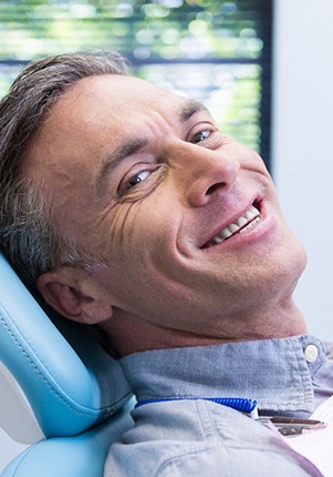 Man smiling in dental chair wearing collared shirt