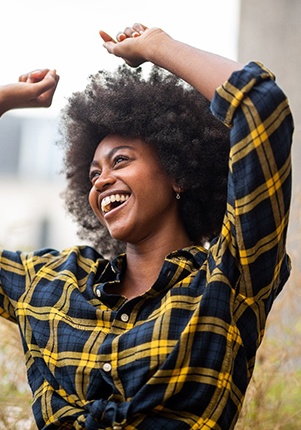 Woman smiling in plaid shirt while dancing outside