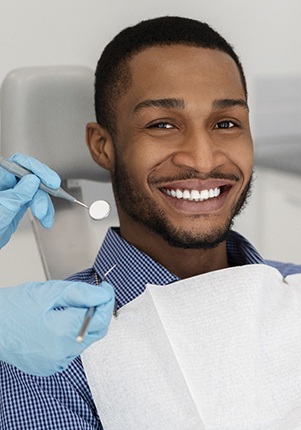 Man smiling in dental chair wearing blue collared shirt