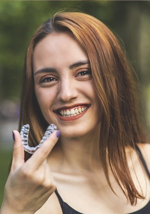 Woman holding up an Invisalign tray